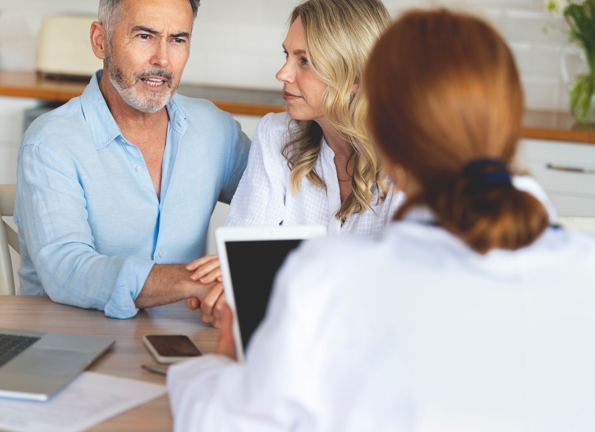 Mature couple talking to a doctor at home.